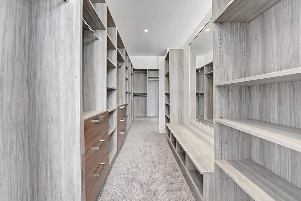 Long walk-in closet with a marble slab counter and open shelving