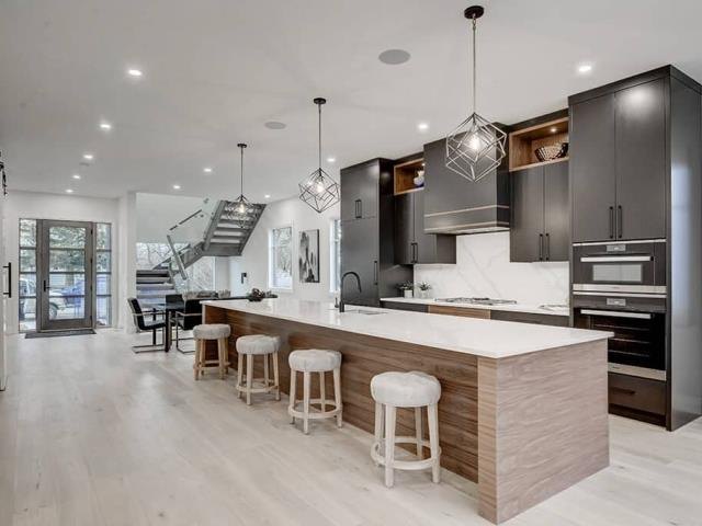 Kitchen with dark base cabinets, light uppers and a wood-clad island