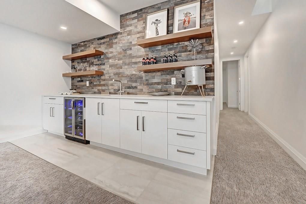 Butler's pantry with white cabinets, a beverage fridge and a stone-clad feature wall