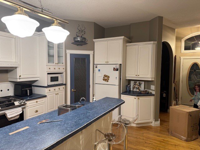 The kitchen before the rebuild, with dated white cabinets and a dark laminate peninsula