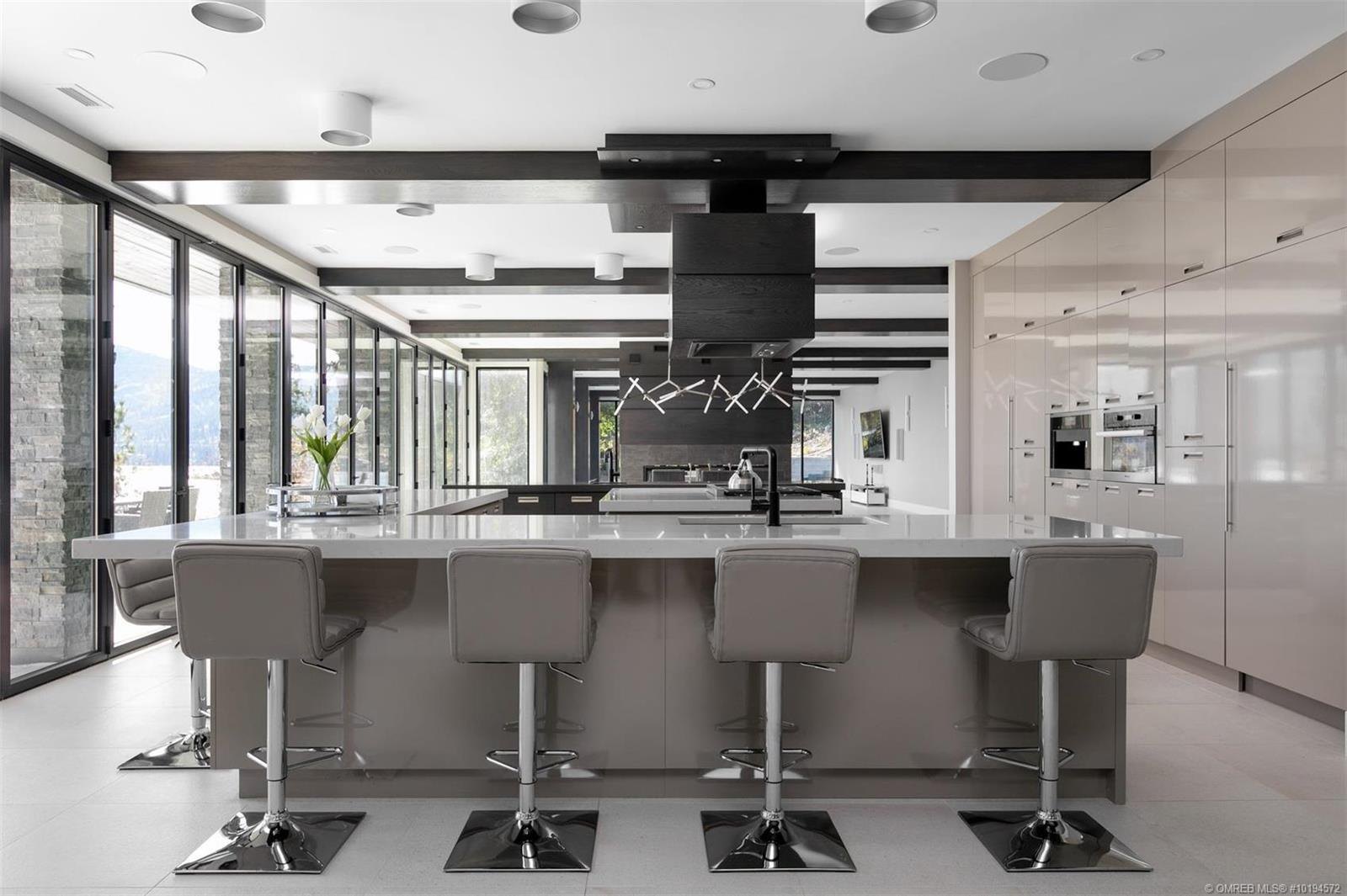 White kitchen with a black range hood and a full-height glass wall