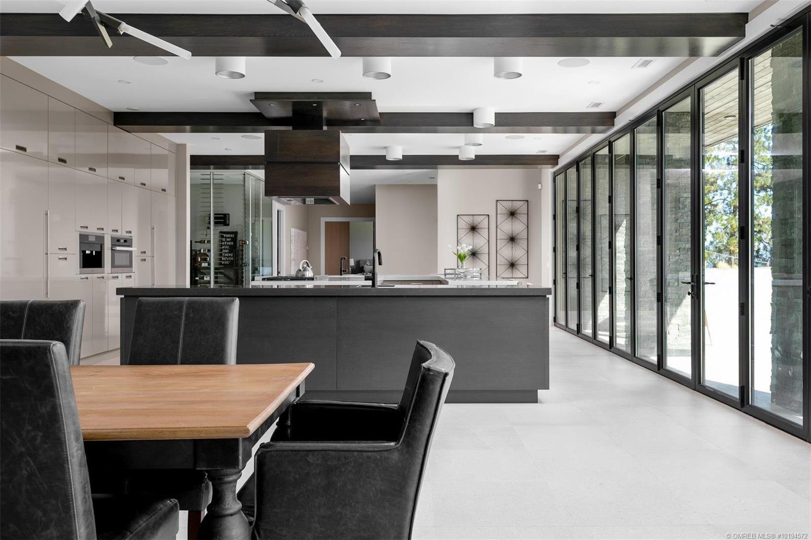 Open dining and kitchen space with dark cabinetry and a folding glass wall