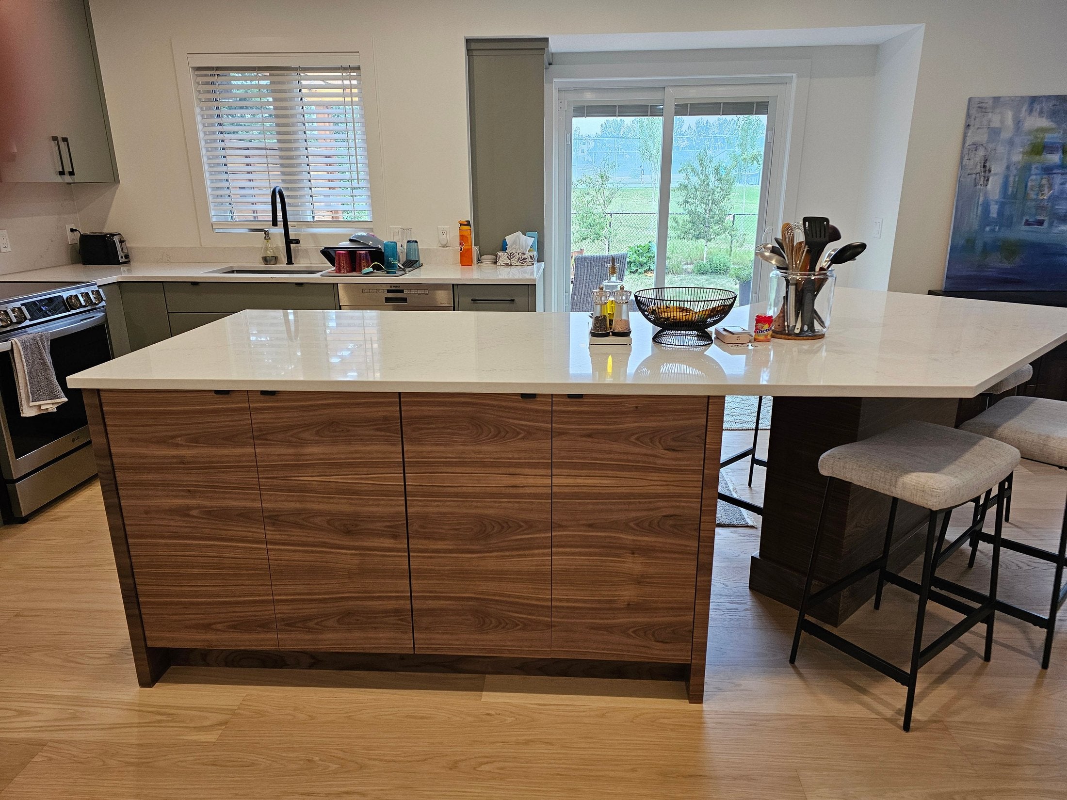 Walnut kitchen island with a waterfall quartz counter and full-height cabinetry behind