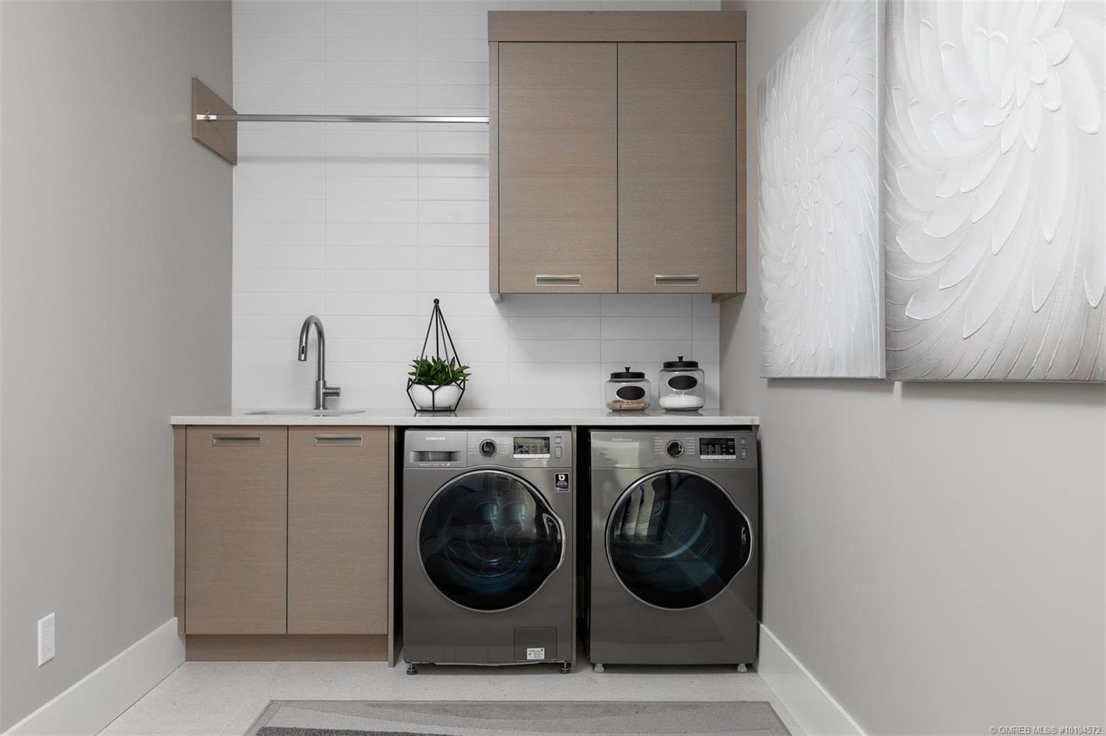 Laundry room with tall pale timber cabinetry above a washer and dryer